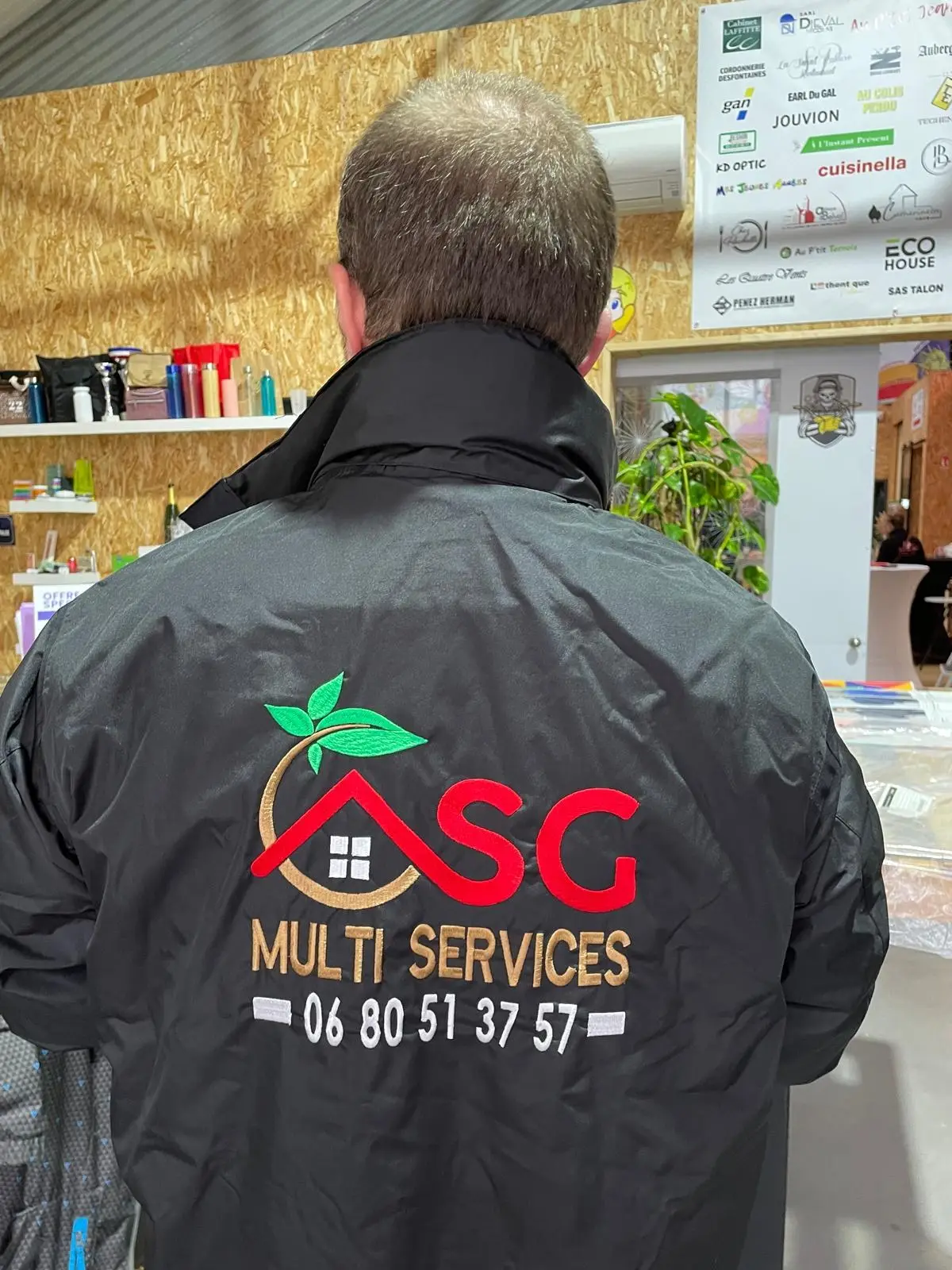 Logo ASG Multi Services avec maison, feuilles et numéro de téléphone brodé dans le dos d'une veste noire