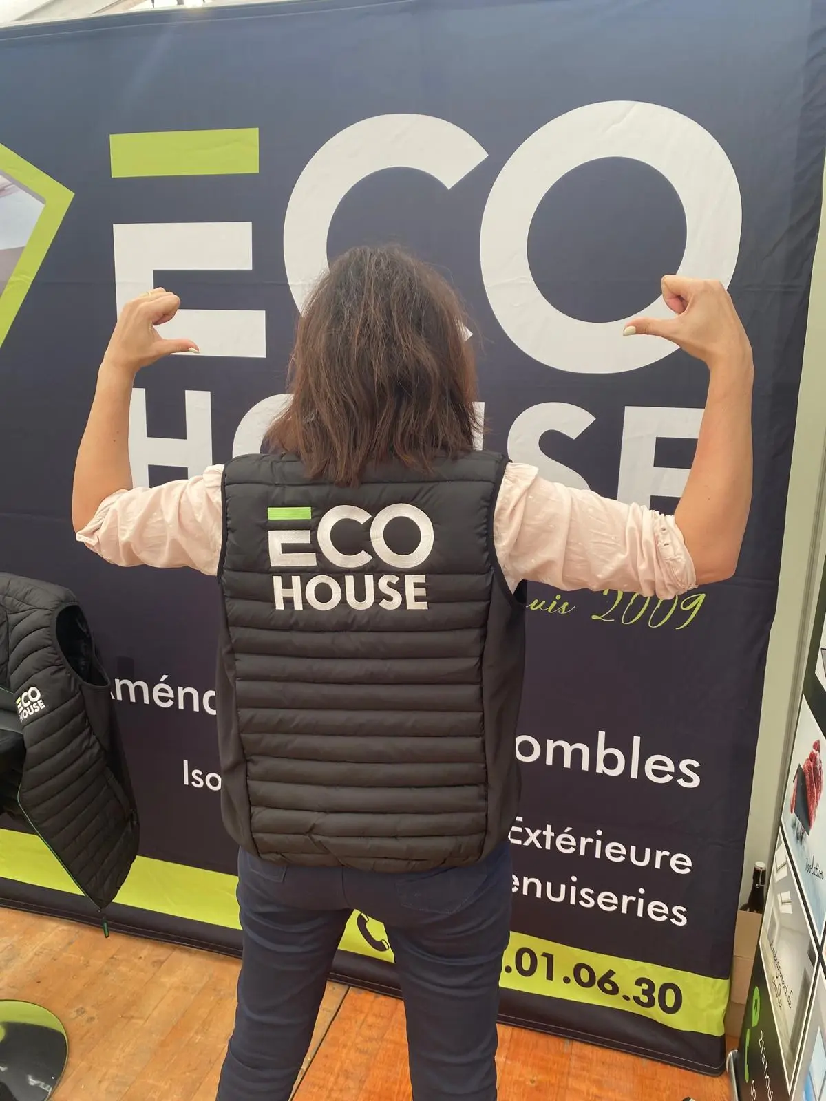 Collaboratrice d'Eco House de dos, portant une doudoune sans manches noire avec le logo Eco House brodé en blanc