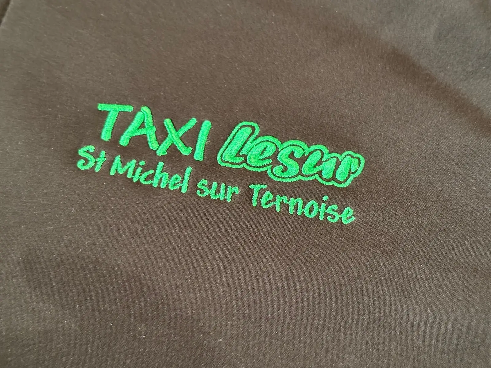 « Taxi Lesur St Michel sur Ternoise » brodé en lettres vertes sur un tissu noir